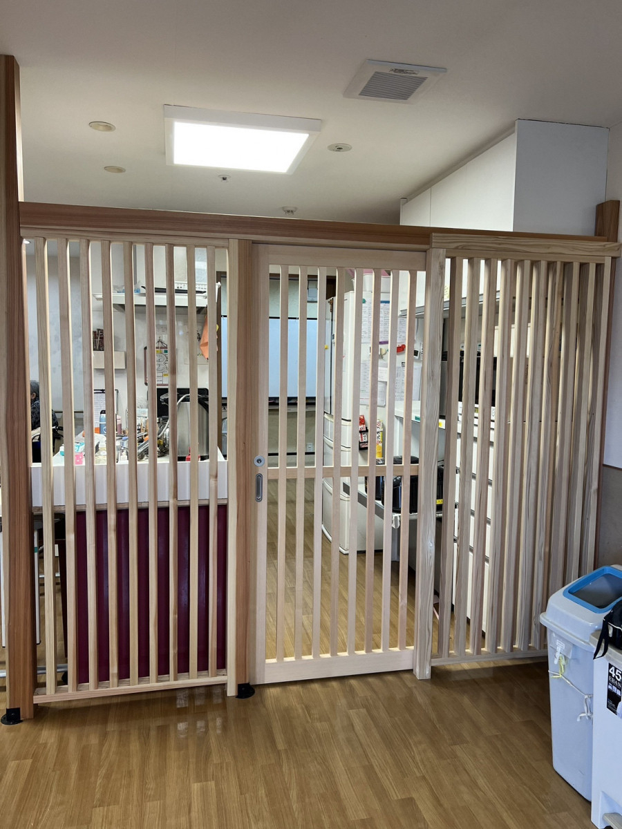 小島サッシトーヨー住器の「見守り」と「安心」を木のぬくもりで繋ぐ。老人ホームのキッチンに施したオーダーメイドの格子壁。の施工後の写真1