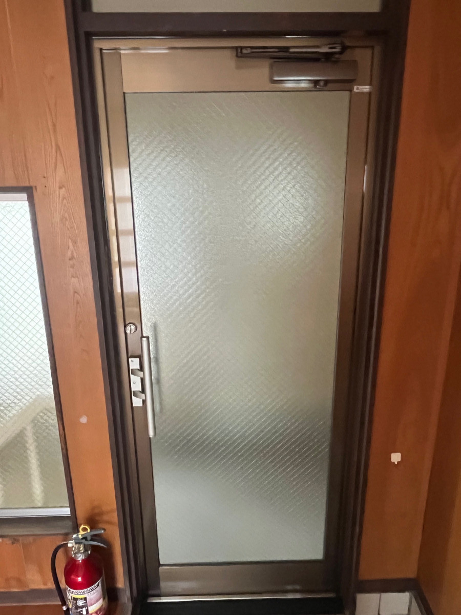 原田硝子店の重厚な木製ドアから、明るく開放的なガラスドアへの施工後の写真1